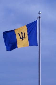 Barbados flag waving on a sunny day with clear blue sky in the background.