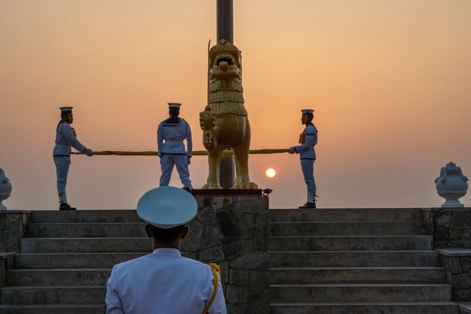 Sri Lankan naval officers conducting a flag ceremony at sunrise in Colombo.