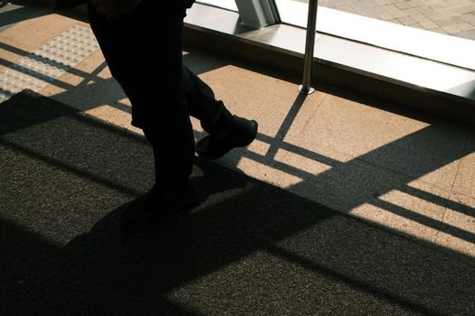 Shadow play of an individual walking inside a building with sunlight streaming through the windows in Jakarta.