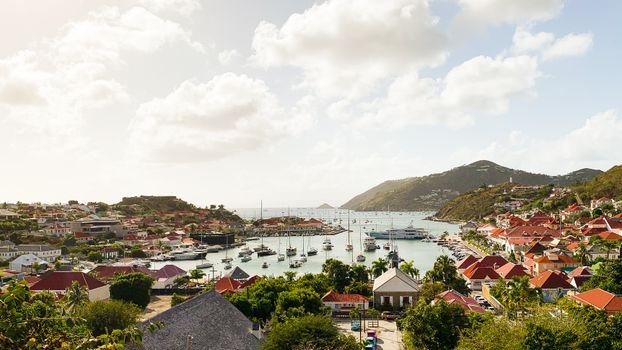 High angle of maritime transport in bay and small town on coast against high hill