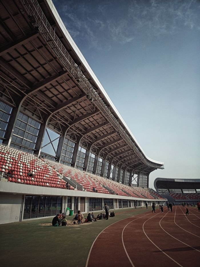 Capture of a modern stadium grandstand in Huaibei Shi, China, showcasing its architectural design and track.
