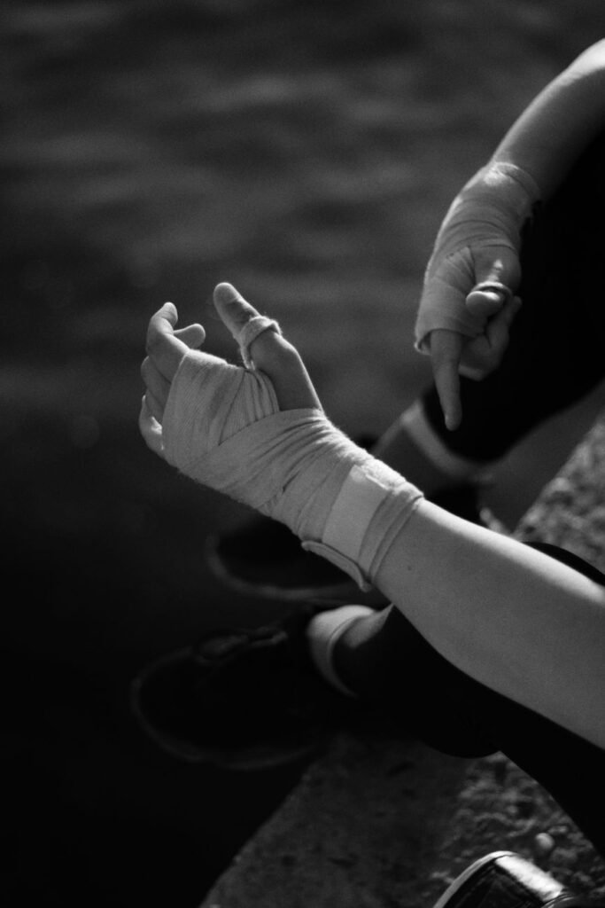 Dramatic black and white photo showing wrapped hands against a water backdrop, conveying injury or preparation.