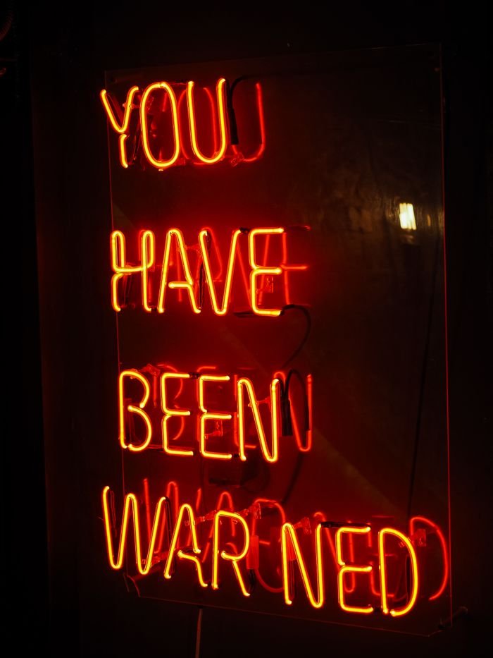 Bright neon sign with the warning message 'You Have Been Warned' glowing in the dark.
