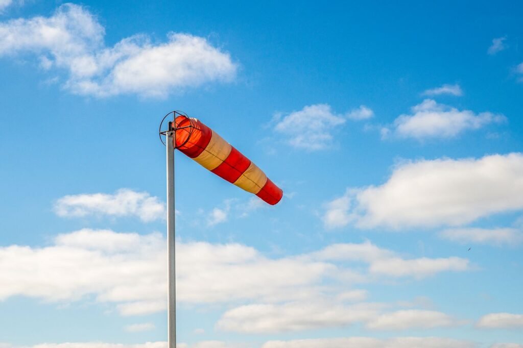 A vibrant windsock indicating wind direction against a picturesque blue sky with clouds.