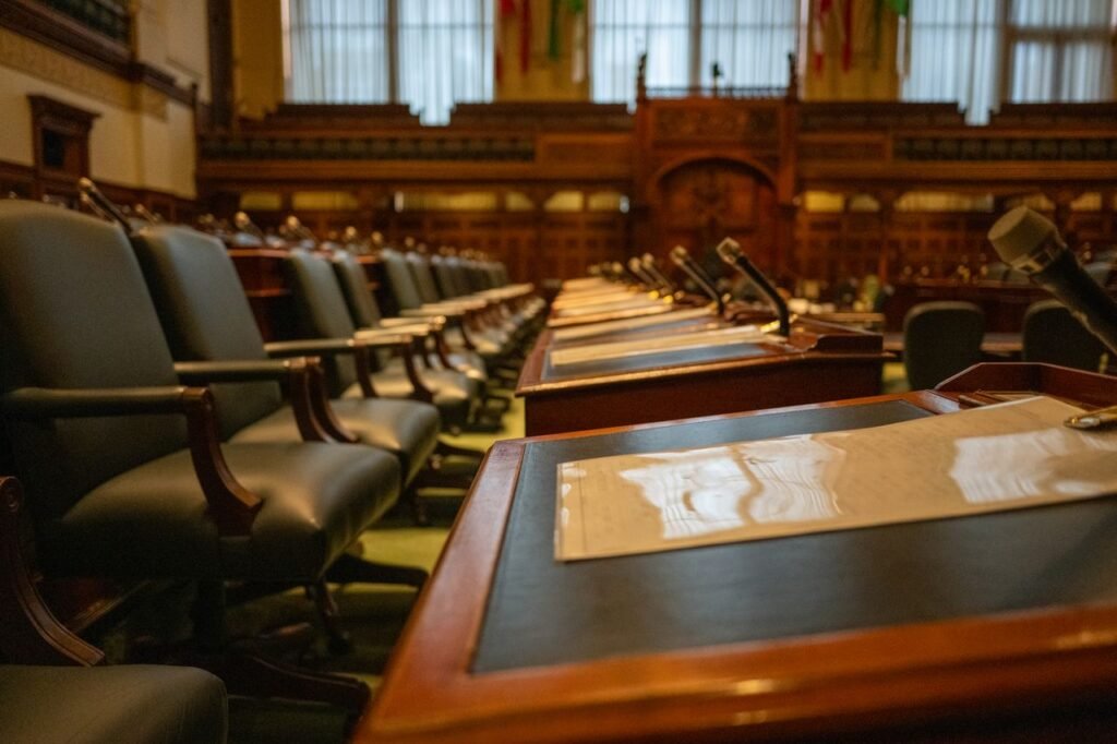 A detailed view of an empty legislative chamber with rows of desks and microphones, evoking governance.