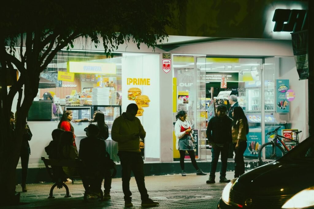 People socializing outside a convenience store at night, capturing urban nightlife atmosphere.