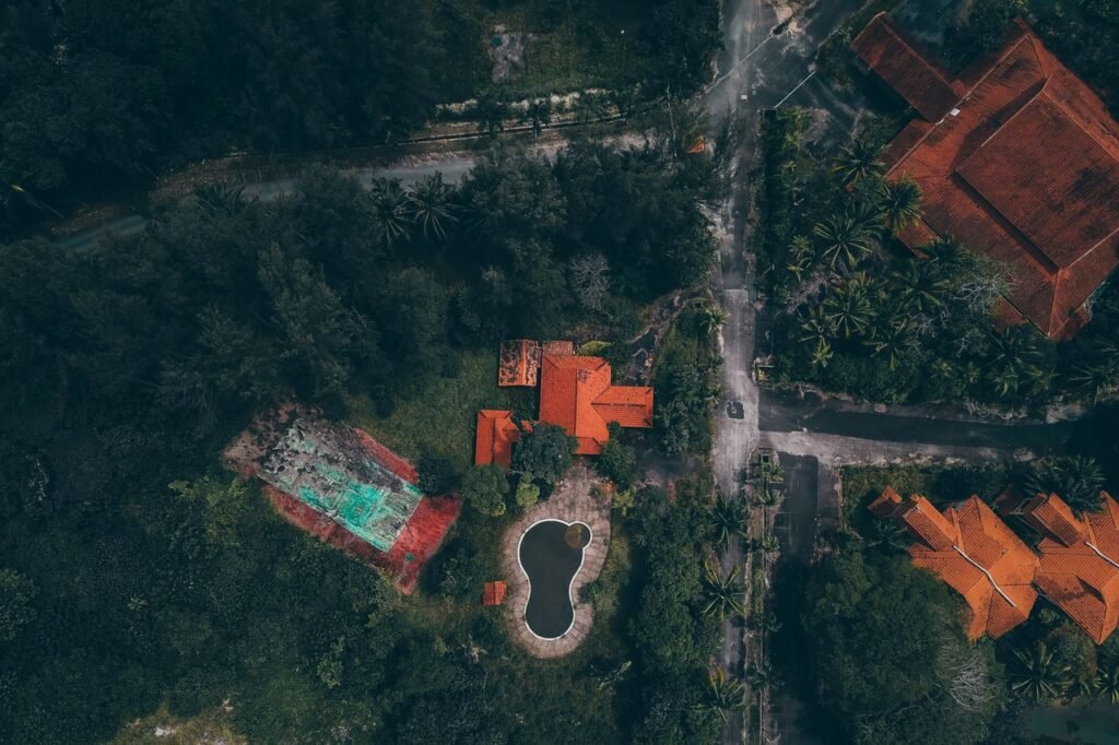 Aerial view of red-roofed houses and pool surrounded by lush greenery in Kijal, Malaysia.